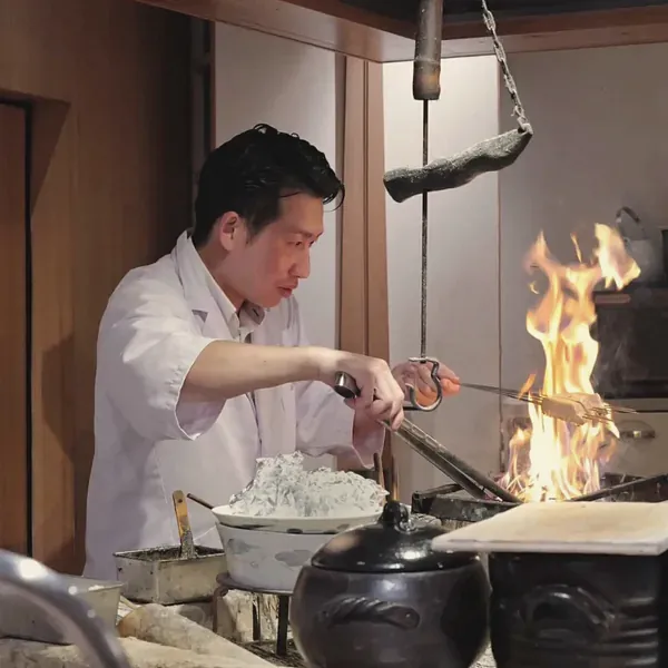 囲炉裏の炎の前で調理する祇園 まんまの店主